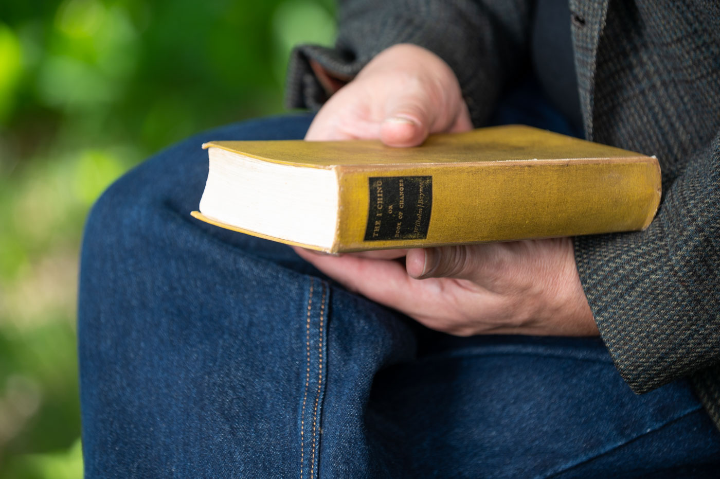 Hands holding a well-worn yellow copy of the Wilhelm/Baynes I Ching