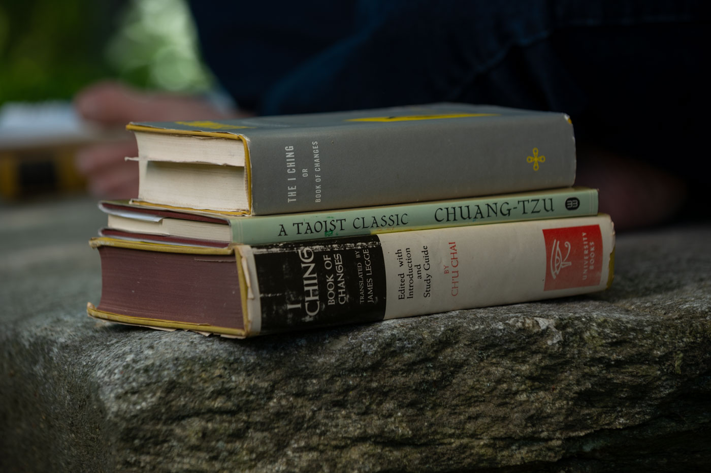 A stack of vintage I Ching and Chuang-Tzu volumes resting on stone